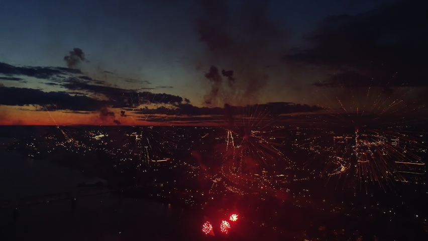 Aerial View Fireworks City Sky. New Year Eve Fly Drone Scene. City Celebrate Night Lights. Flight Above Sparks Firework Explode Festive. Bright Explosion Fireworks on Evening Urban Skyline Background