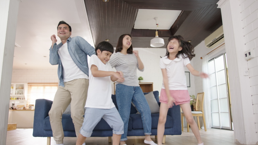 Happy asian family mother, father, son and child daughter dancing in living room at home. Happy moment dancing in home enjoying weekend together. Family spend time together concept. | Shutterstock HD Video #1062883180