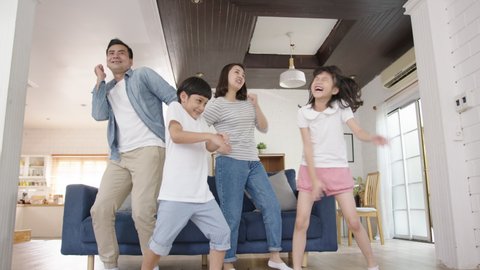 Happy asian family mother, father, son and child daughter dancing in living room at home. Happy moment dancing in home enjoying weekend together. Family spend time together concept.