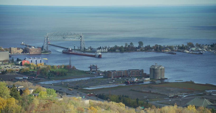 A High Angle Shot of the Duluth Aerial Lift Bridge Raising as a cargo ship returns to the Twin Ports of Lake Superior, water in the background