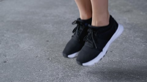 Close-Up of Women's Feet in Sports Shoes Jumping Rope Dressed in Sportswear Black Top and Leggings, is In the Gym