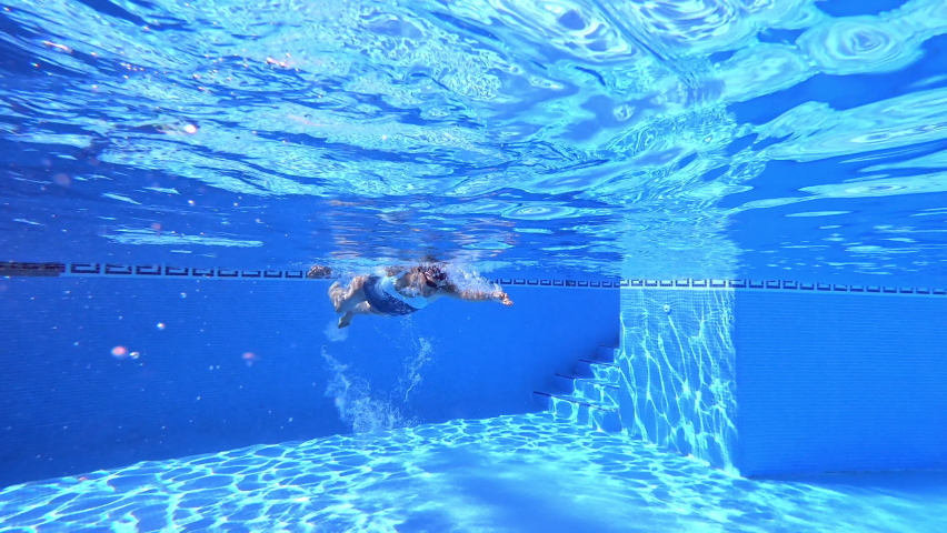 Underwater view of sport woman with googles and cap swimming crawl style in clear water of pool approaching
 | Shutterstock HD Video #1062884863