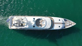 Aerial tracking top down video of luxury yacht cruising near tropical port