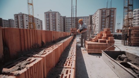 Moving along a wall of red bricks to a builder who builds it in a way