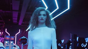 Beautiful caucasian woman in white futuristic costume and glasses walking in night club in city of future. Blue and violet neon light. Trendy stylish millennial female. VR club, future technology