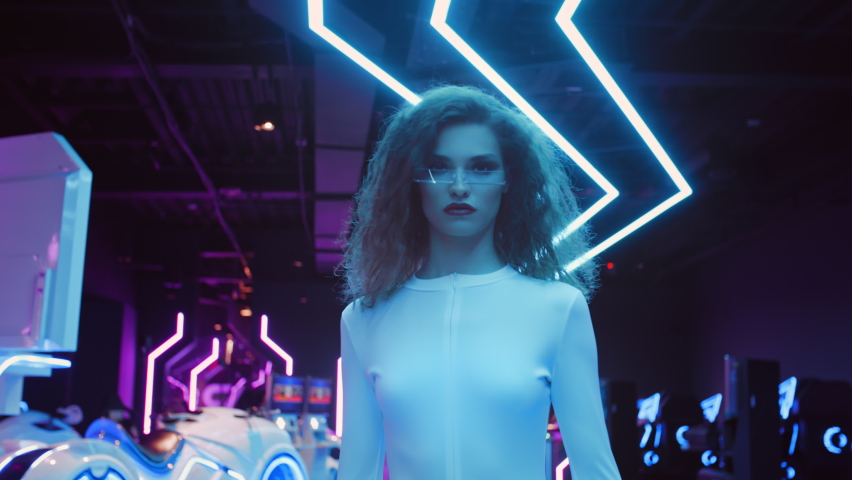 Beautiful caucasian woman in white futuristic costume and glasses walking in night club in city of future. Blue and violet neon light. Trendy stylish millennial female. VR club, future technology | Shutterstock HD Video #1062894145
