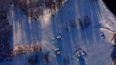Aerial looking down over houses in a winter forest at sunset in Senja, Norway 