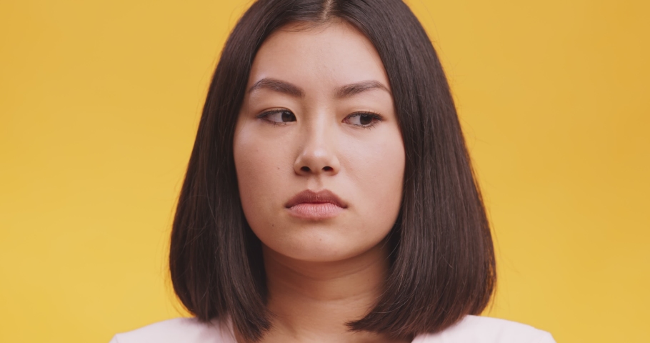 Disgusting odour. Discontent asian woman frowning face, smells something awful, feeling aversion, orange studio background Royalty-Free Stock Footage #1062897664
