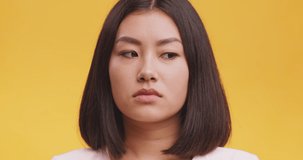 Disgusting odour. Discontent asian woman frowning face, smells something awful, feeling aversion, orange studio background
