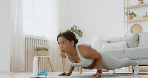 Strength workout. Young sporty african american woman practicing push ups exercise at home, slow motion Video Stok