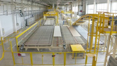 Manufacture of drywall or gypsum board by conveyor on factory. Production of building materials or plasterboard sheet.