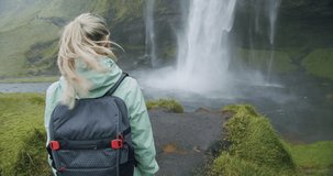 Women with backpack walking towards Seljalandsfoss waterfall Iceland