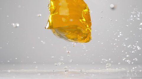 Yellow jelly falling down. Falling jelly on white wet surface in slow motion. Сlose up. 