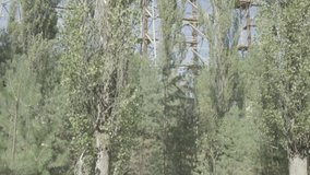 Fast tilt down the Duga-1 radar station in Chernobyl Ukraine with trees in the foreground. Ungraded Log Footage