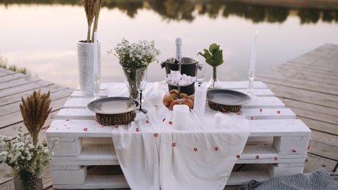 White wooden table with romantic decoration. Romantic decor elements for marriage requests. Romantic outdoor dinner. Composition with candle decoration. Concept of marriage applications.
