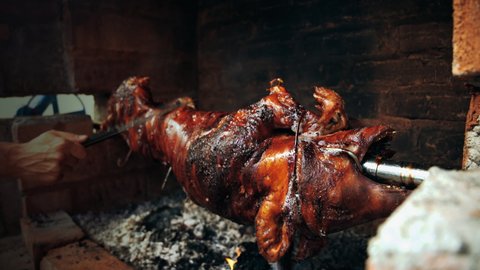 Serbian "Pecenje" roasted pig on a skewer turning over hot ash for an Orthodox event called "slava"