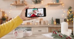 Close up of smartphone screen with online video chat with different people. Woman hand holds cellphone talking on multiple video call with family and relatives on Christmas Eve. New Year celebration