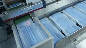 Production of medical three-layer blue or white masks. New masks move on a conveyor belt. Face masks for the work of doctors with patients. Making protective masks during the coronavirus pandemic - Powered by Shutterstock - Get 15% off with code: PIKWIZARD15