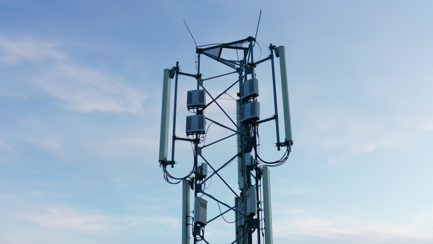 Telecommunications tower carrying broadcasting antennas for gsm, 3G, 4G and 5G cellular networks. Aerial drone shot of a tall metal structure with equipment for mobile telephony and internet. Royalty-Free Stock Footage #1062921574