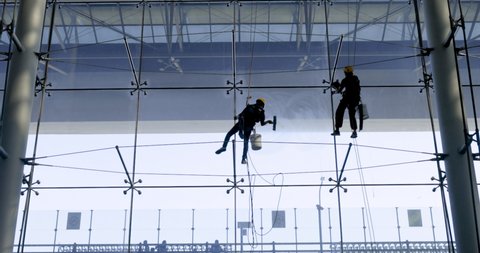 SUVARNABHUMI AIRPORT, BANGKOK, THAILAND - November 19 , 2020 : Two male workers cleaning windows on a high glass Suvarnabhumi Airport building, Bangkok Thailand