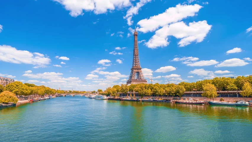 A timelapse of the Eiffel Tower along the river Seine with flyboats passing by with motion blur.Sunny but cloudy autumn day with golden yellow leaves,paris city riverside bay view bridge panorama