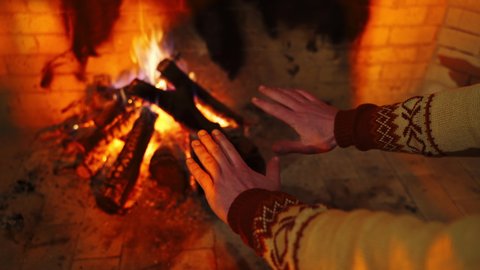 Hands of the man closeup. Male is warming hands near the bonfire at the twilight's inside. Cold season concept.