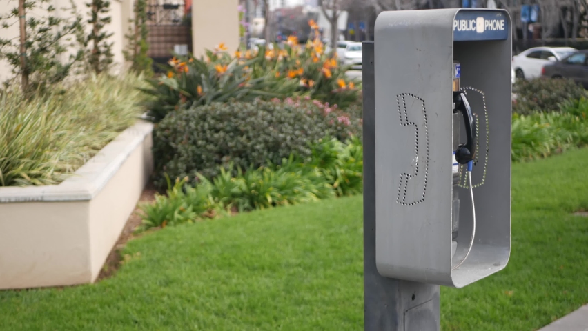 Retro coin-operated payphone station for emergency call on street, California USA. Public analog pay phone booth. Outdated technology for connection and telecommunication service. Cell handset on box.