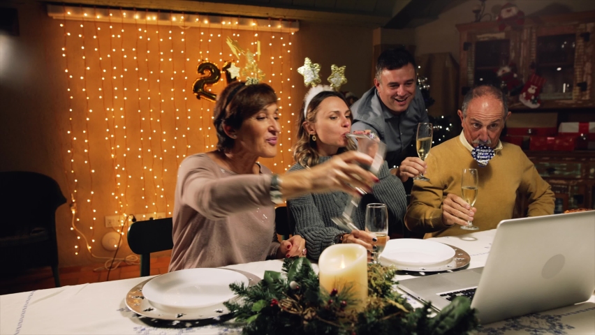 Funny and excited family greeting their relatives on New Years Eve, with a video call, toasting with champagne glasses. Online communication during Coronavirus Pandemic year, 2020-2021. Royalty-Free Stock Footage #1062937618