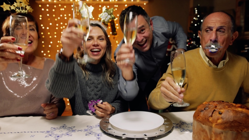 Tracking shot of excited family toasting with champagne for New Year's 2021, looking at camera. POV of a friends video call. Concept of social distance due to coronavirus, Covid-19 pandemic. Royalty-Free Stock Footage #1062937621