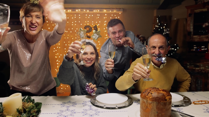 Tracking shot of excited family toasting with champagne for New Year's 2021, looking at camera. POV of a friends video call. Concept of social distance due to coronavirus, Covid-19 pandemic. | Shutterstock HD Video #1062937621