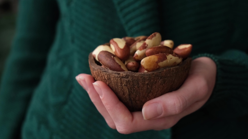Woman eating brazil nuts. Healthy vegan vegetarian food, trendy superfood nuts | Shutterstock HD Video #1062937651
