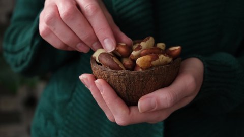 Woman eating brazil nuts. Healthy vegan vegetarian food, trendy superfood nuts
