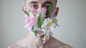 Closeup portrait of young man wearing face mask decorated with flowers.  concept video. a man in a protective mask made of flowers. a man in a medical mask decorated with natural flowers. closeup.