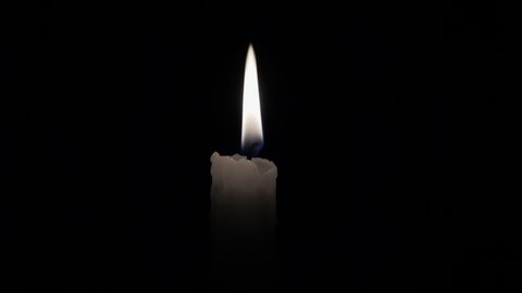 Candle. Match lights the candle wick. Light a candle in the darkness. Flame of a candle lit on a black background.