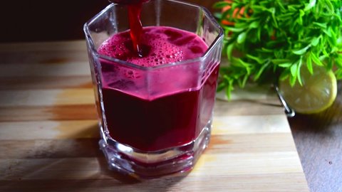 Beetroot juice pouring into the white glass. Red beet juice serving into the glass. Red juice on white glass. 