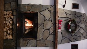 Fire burn in a fireplace decorated with wreath and candles on Christmas eve. New Year holidays celebration. Vertical video