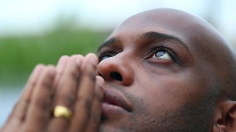 Christian black African man praying, close-up mixed race person eyes looking at sky