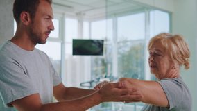Young physiotherapist worker stretching arms of elderly woman assisting physical medical exercise recovery after injuries. Rehabilitation. Treatment concept. - Powered by Shutterstock - Get 15% off with code: PIKWIZARD15