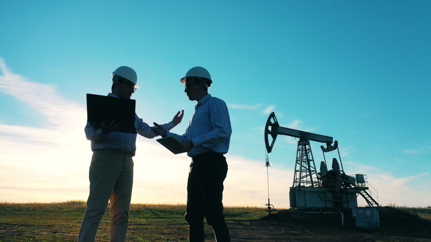 Two engineers are discussing a project at the oil extraction site. Oil and gas industry concept. Royalty-Free Stock Footage #1062958414