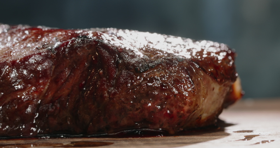 Close up shot of a juicy freshly grilled steak. Big piece of tasty meat straight from the grid. Smoke rising from delicious meal on chef's preparation table 4k footage Royalty-Free Stock Footage #1062959557