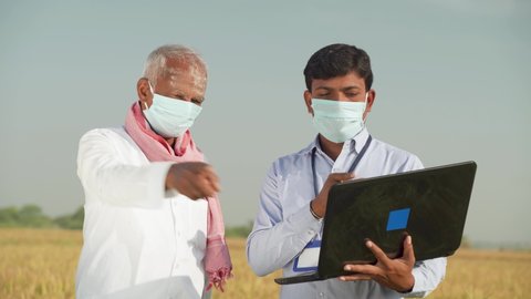 Farmer and banker or corporate government officer discussing on laptop about crop yield, credit and loan subsidy while both worn face mask due to covid-19 coronavirus pandemic
