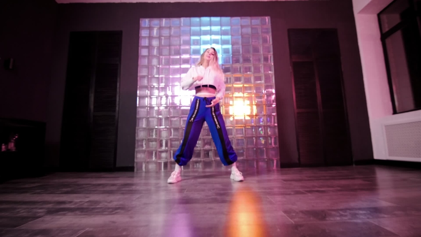 Cheerful young woman dancing hip hop, freestyle, dancehall in a choreographic studio.