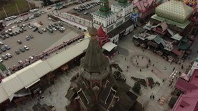 Flies up from the old wooden church and lowers the camera down, in the frame the city square and the golden cross, aerial video