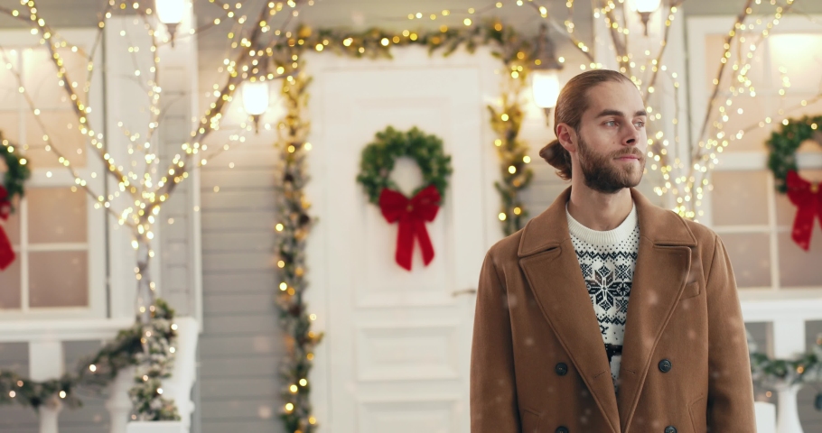 Portrait of handsome young Caucasian bearded man in good mood standing on decorated xmas street in city on New Year. Male looking at camera outdoors. Holiday season. Winter concept. Merry Christmas