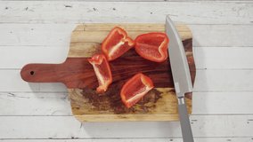 Time lapse. Flat lay. Cutting organic red bell peppers on a wood cutting board.