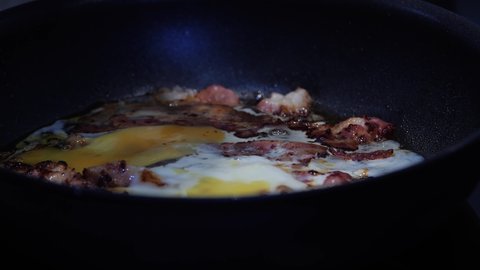 Bacon and egg are cooked in a pan