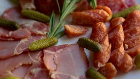 Meat snacks served for wine party in restaurant.  Delicious sliced Spanish jamon,smoked ham,hot pepperoni sausages served on white ceramic plate for dinner