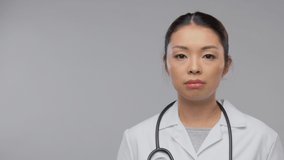 medicine, profession and healthcare concept - video portrait of happy smiling asian female doctor in white coat with stethoscope over grey background