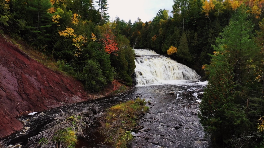 Beautiful autumn aerial following the Potato River upstream to the incredible Lower Potato River Falls waterfall as water cascades down the rocky tiers.