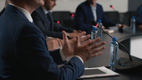 Political speaker talks at meeting room of modern business forum. Adult man in suit discusses partnership at conference in convention hall. Expert group of colleagues works at official event closeup - Powered by Shutterstock - Get 15% off with code: PIKWIZARD15